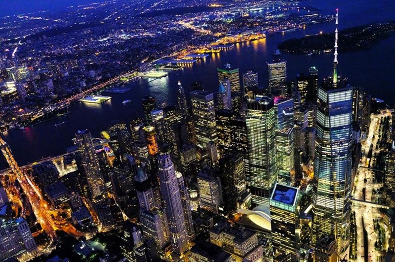 Aerial night view of Manhattan skyline, illuminated skyscrapers, and Hudson River with glowing city lights