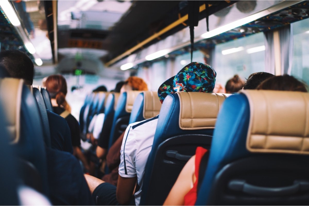 A photograph of the inside of a coach filled with people, with headrests visible