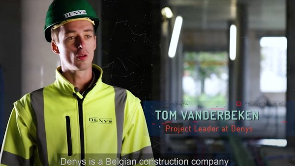 An image from a video of a construction worker standing at a site with a hard hat and hi-vis on
