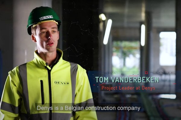 An image from a video of a construction worker standing at a site with a hard hat and hi-vis on